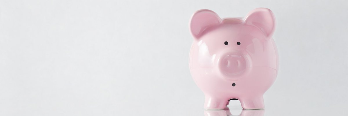 A hand holding a hammer over a worried-looking piggy bank.