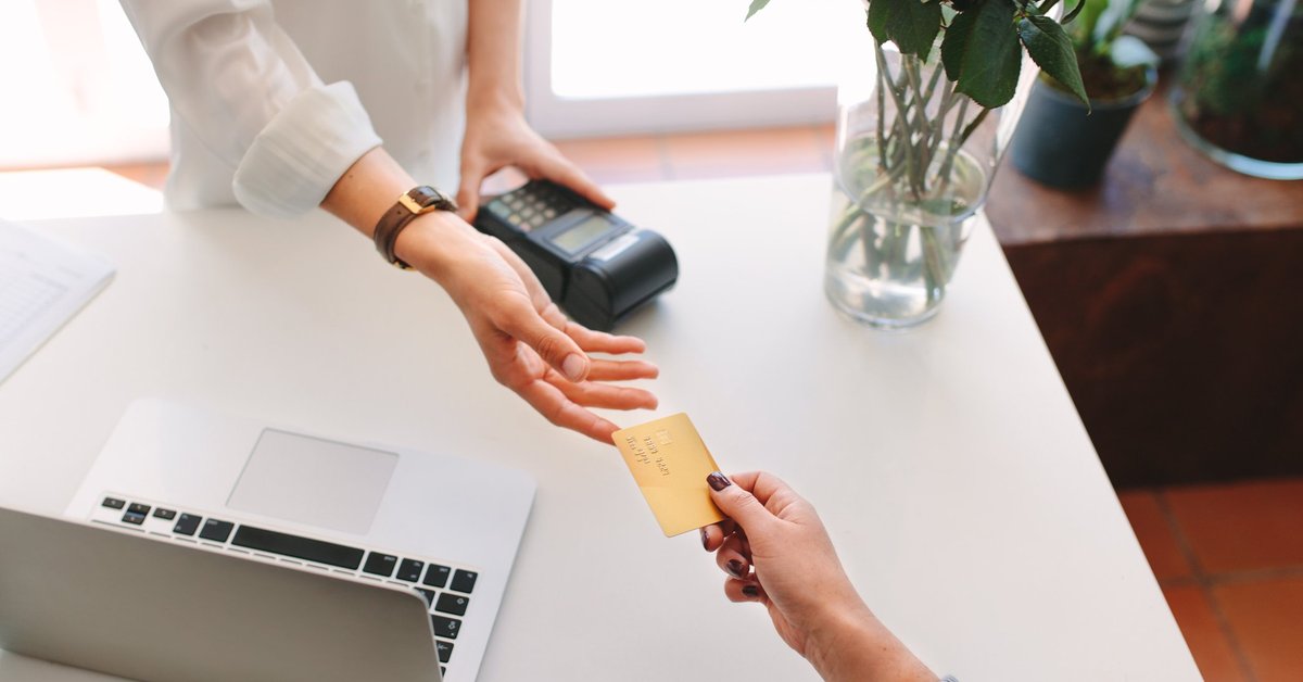 A woman handing her credit card to a store employee for payment.