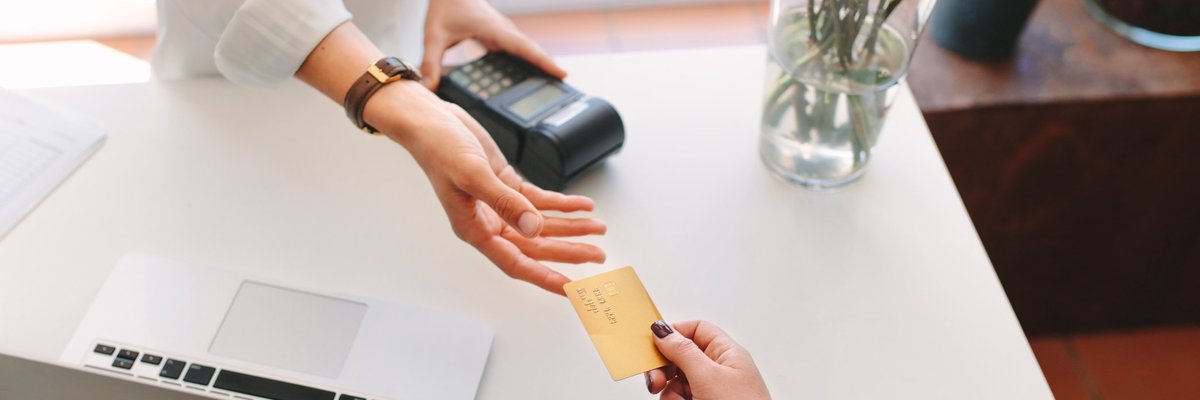 A woman handing her credit card to a store employee for payment.