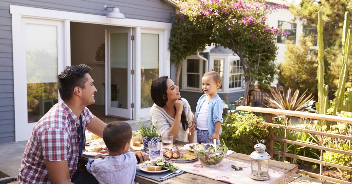 A happy family in eating lunch in their sunny backyard.