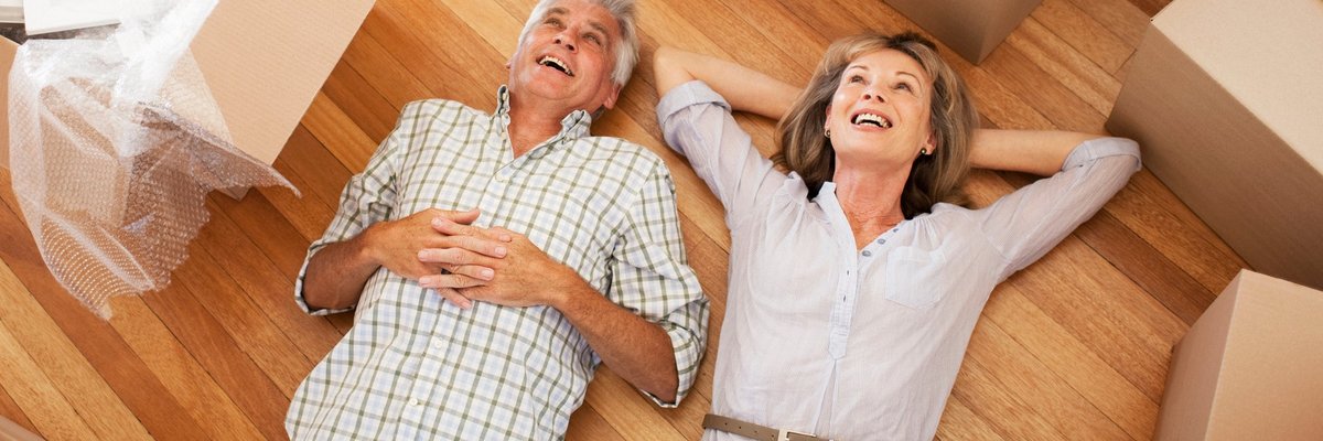 Happy, mature couple laying on the floor surrounded by moving boxes.