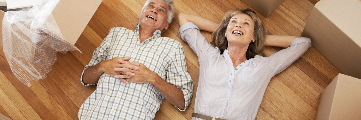Happy, mature couple laying on the floor surrounded by moving boxes.