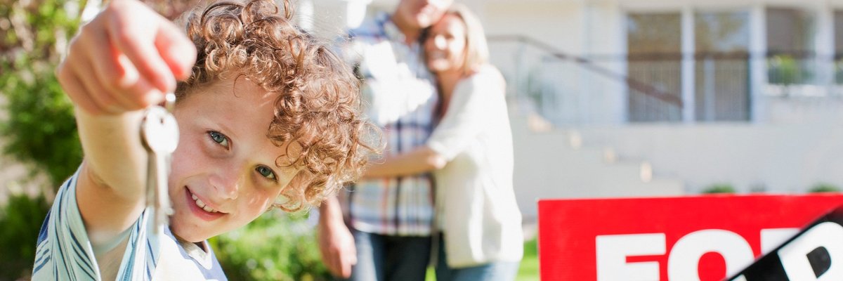 Family standing in front of sold house holding a key.