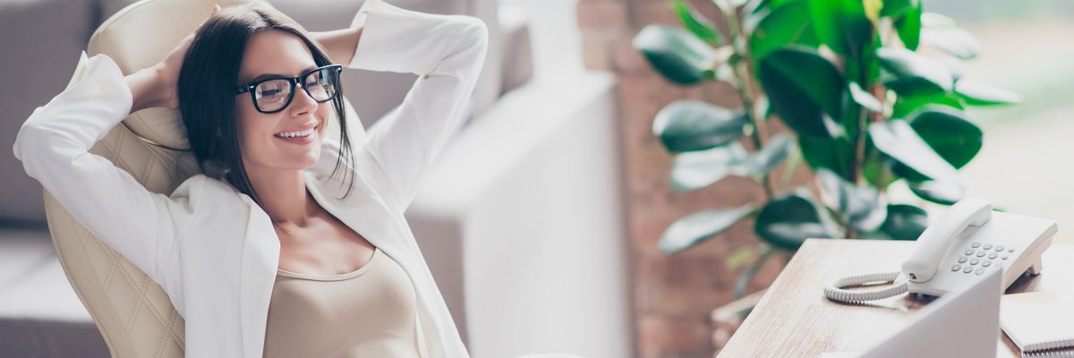 Content woman in glasses laying back in office chair with hands behind her head.