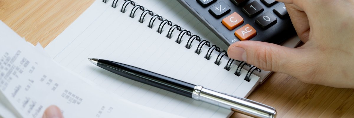 one hand types on a calculator while the other holds some receipts