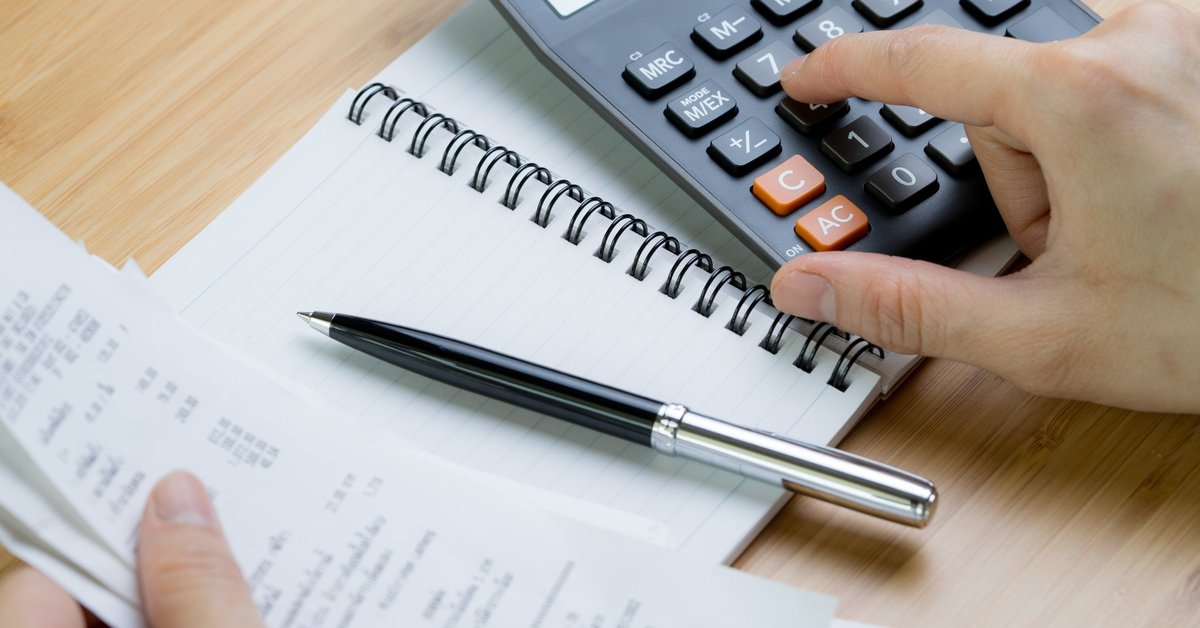 Person checking receipts and using a calculator.