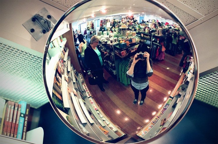 Woman taking her own picture in a convex mirror.