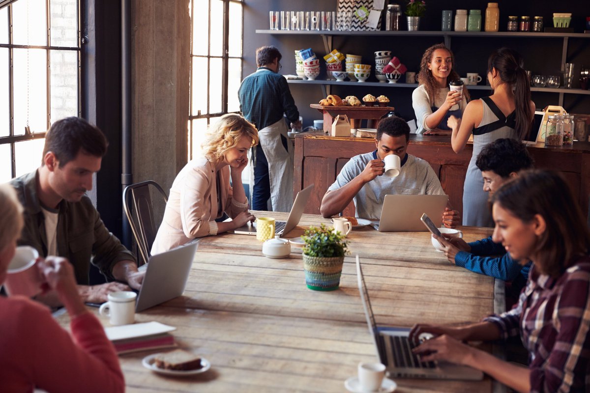People in a cafe drinking coffee and working on laptops.