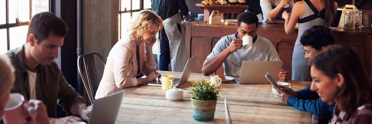 People in a cafe drinking coffee and working on laptops.