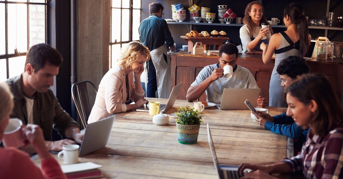 People in a cafe drinking coffee and working on laptops.