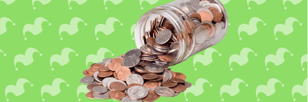 A glass jar tipped over with coins falling out