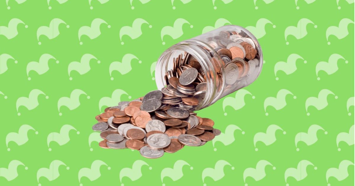A glass jar tipped over with coins falling out