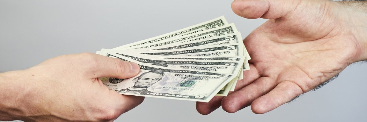 One hand holding cash and another hand reaching out to accept it.