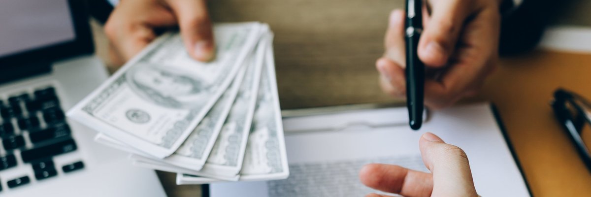Someone signing loan paperwork and being handed money.