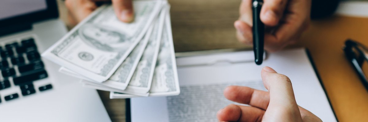 Someone signing loan paperwork and being handed money.