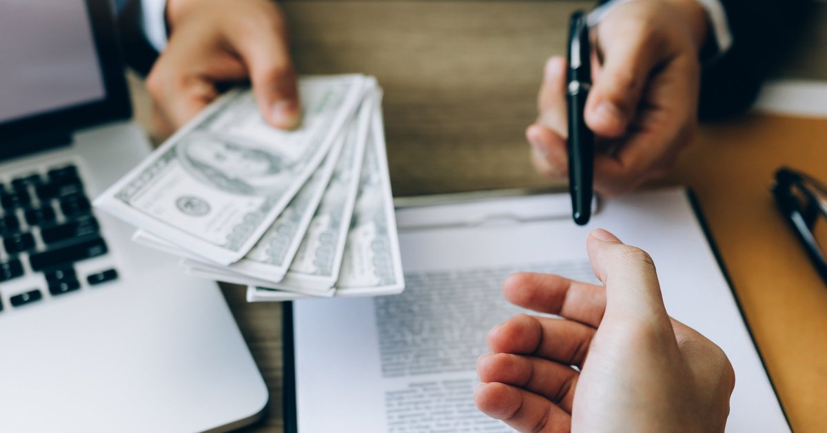 Someone signing loan paperwork and being handed money.