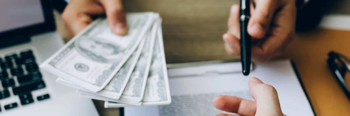 Someone signing loan paperwork and being handed money.