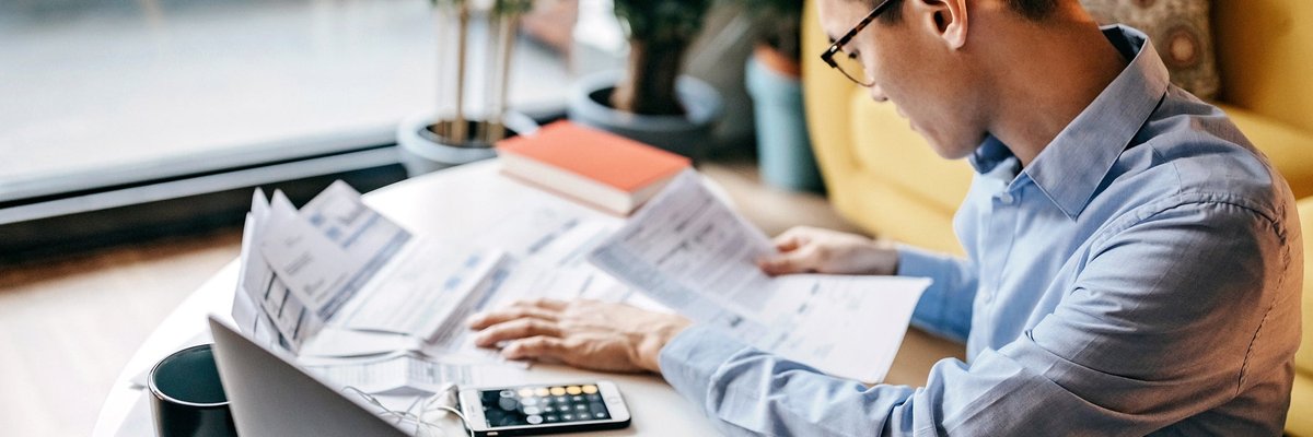 Man using a calculator and looking over documents.