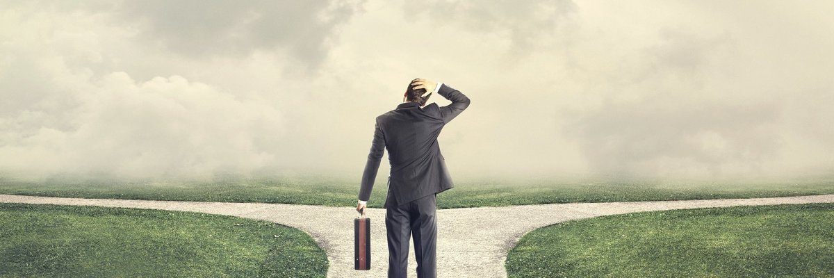 Man looking at two diverging paths and scratching his head