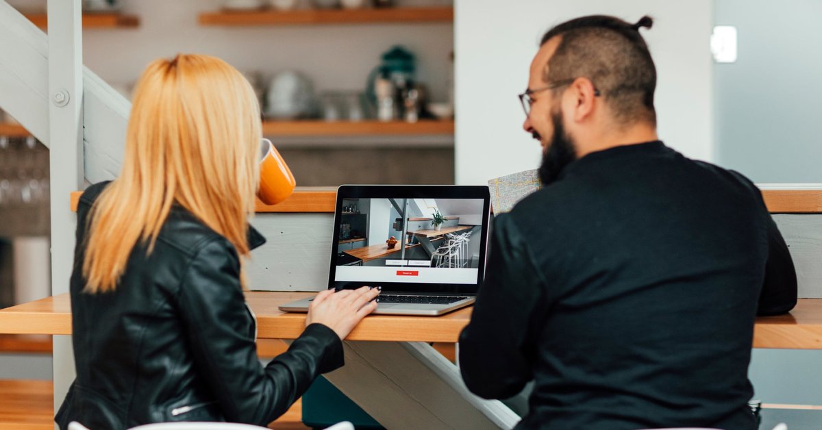 Man and woman look at homes on a laptop.