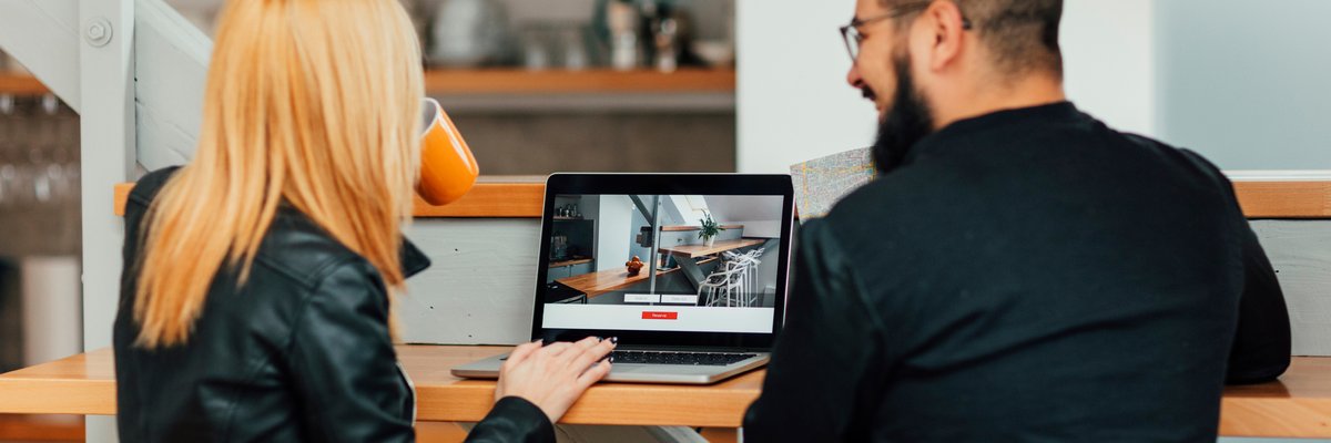 Man and woman look at homes on a laptop.