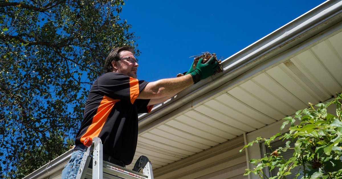 Man cleaning home's gutters.