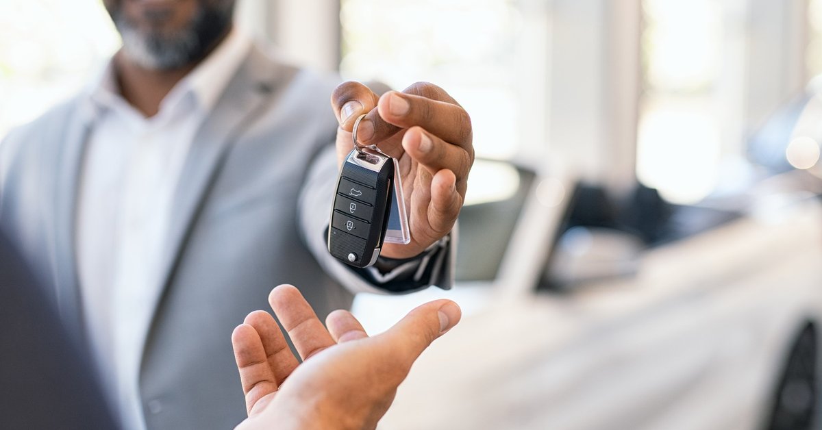 A salesman handing over the keys to a new car.