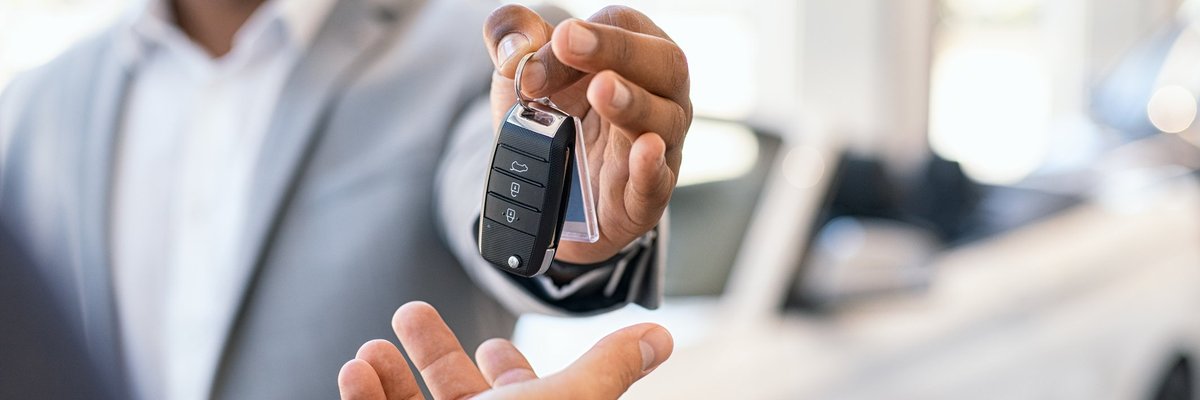 A salesman handing over the keys to a new car.