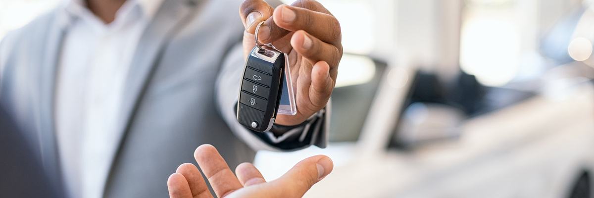 A salesman handing over the keys to a new car.