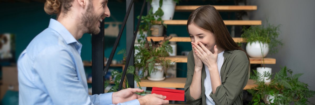 Man hands young girl a gift in an envelope.