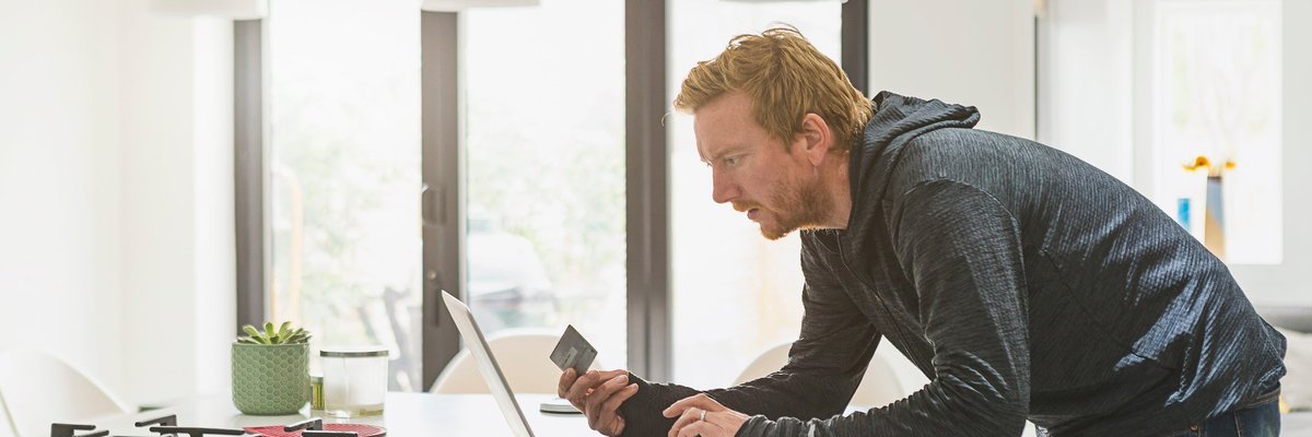 Man holding credit card and using laptop.