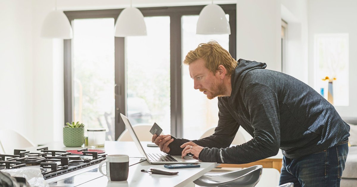 Man holding credit card and using laptop.