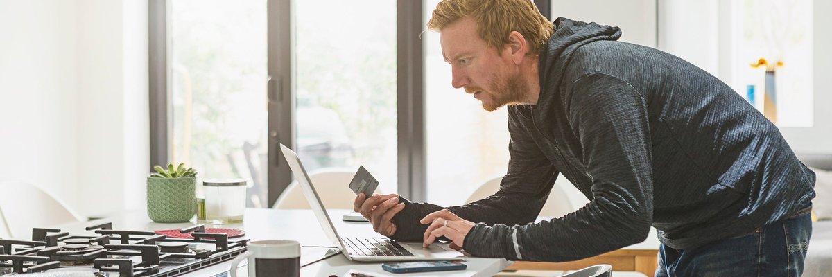 Man holding credit card and using laptop.