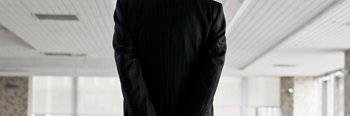 Man in suit with back turned and his hands in handcuffs.