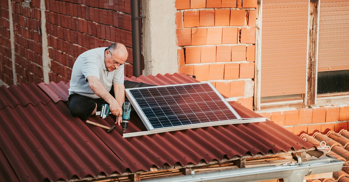 Man installing solar panels on the roof of a home.