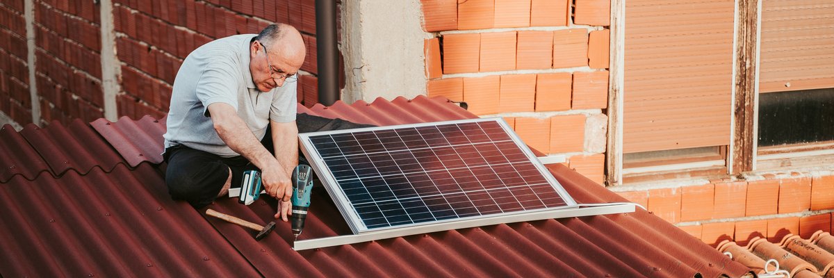 Man installing solar panels on the roof of a home.
