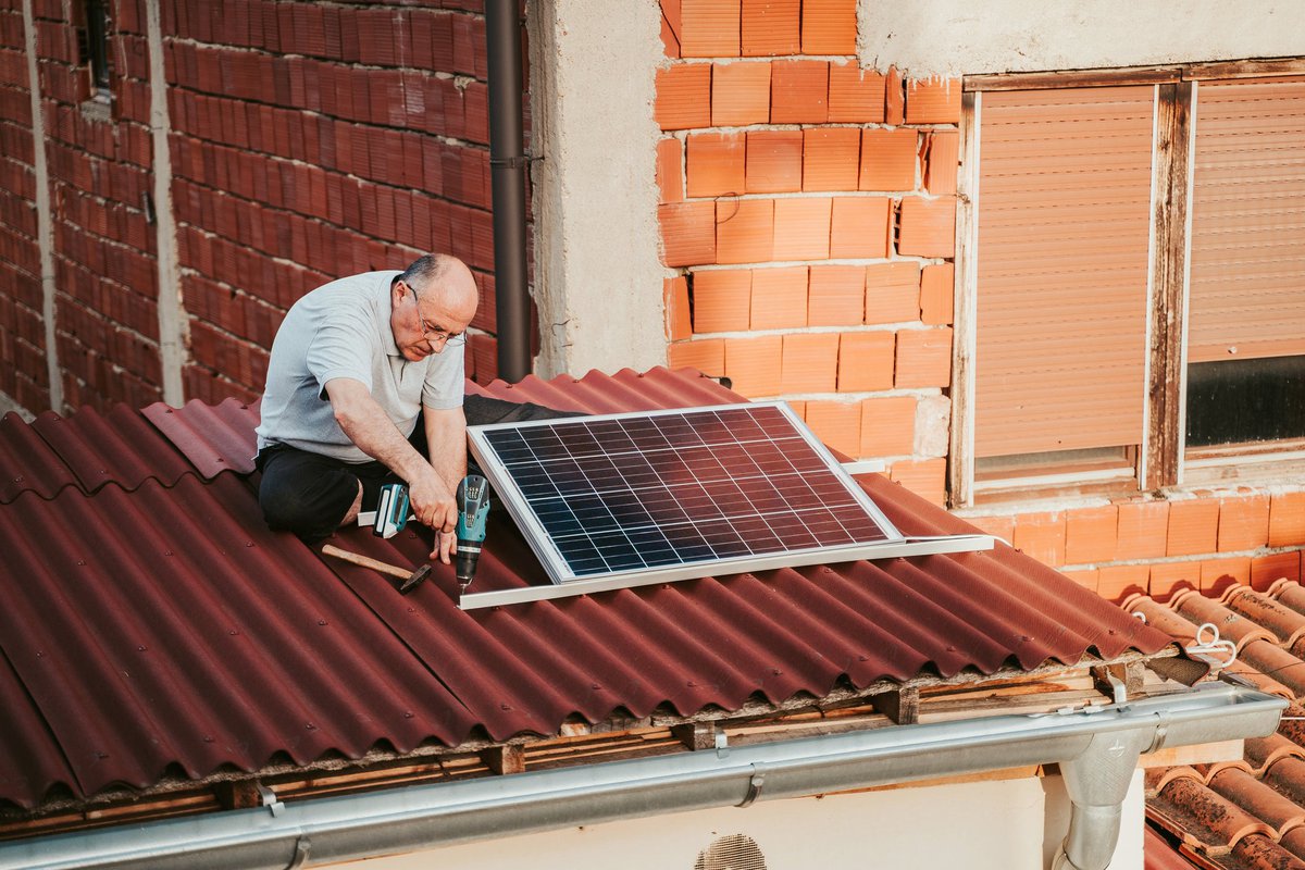 Man installing solar panels on the roof of a home.