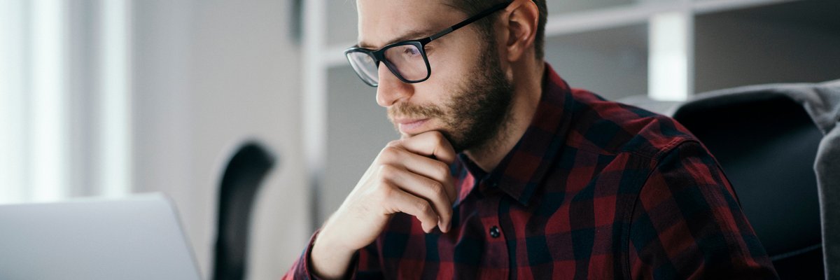 Man appears to be in thought while looking at laptop screen.