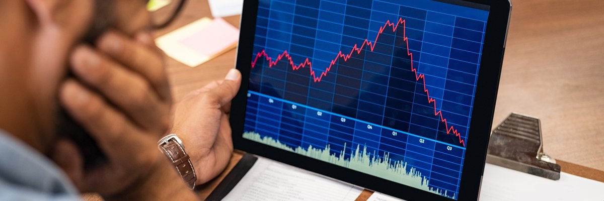 Man looking at tablet with downward trending line graph on it.