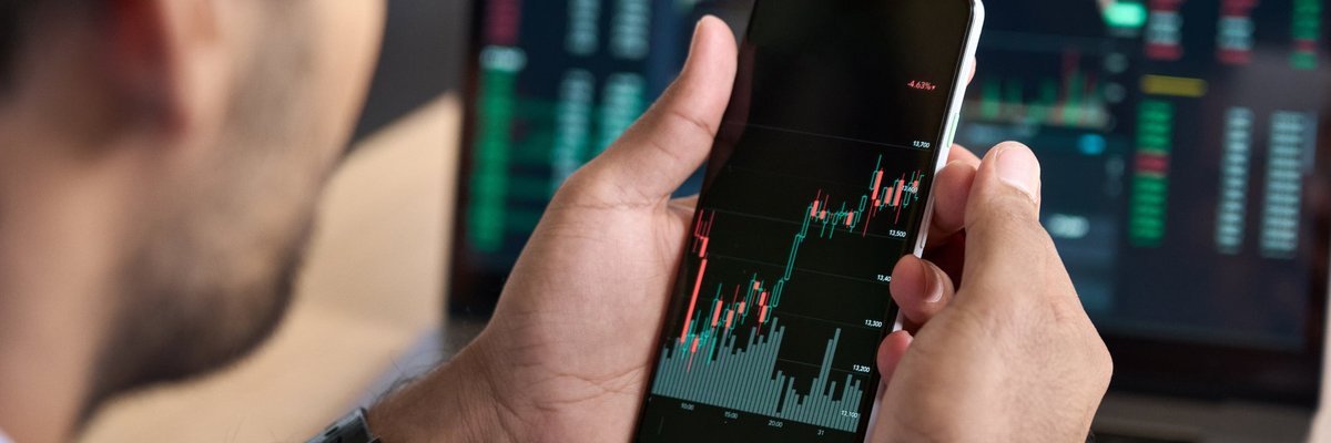 Man looking at upward trending data on his smartphone.