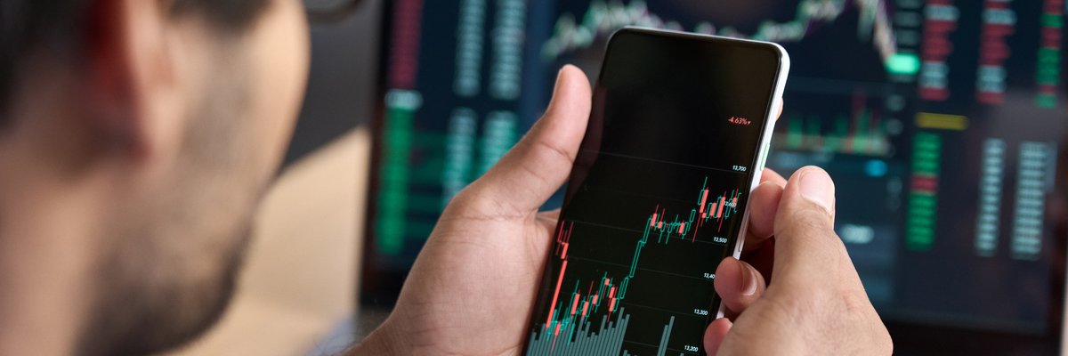 Man looking at upward trending data on his smartphone.