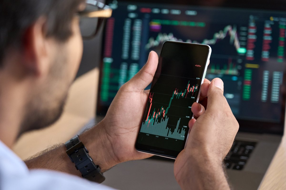 Man looks at upward data on his smartphone.