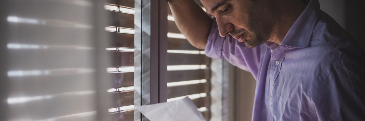 Man looks saddened by paper that he's reading.