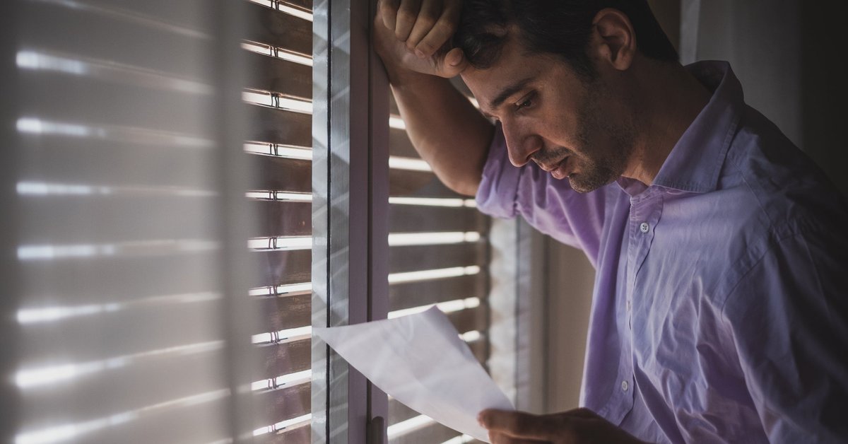 Man looks saddened by paper that he's reading.