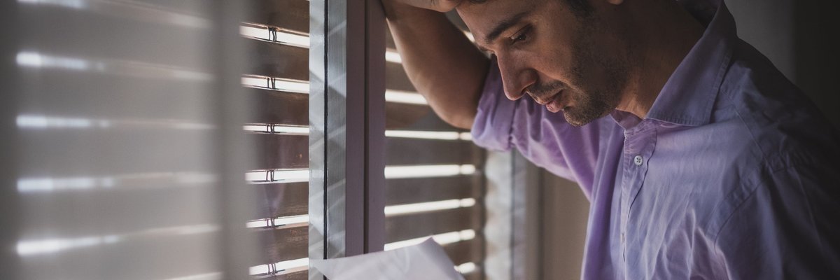 Man looks saddened by paper that he's reading.