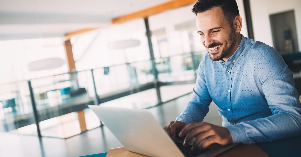 A man smiling while using his laptop.