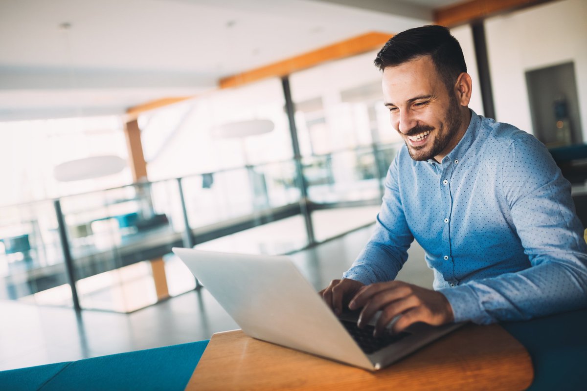 A man smiling while using his laptop.