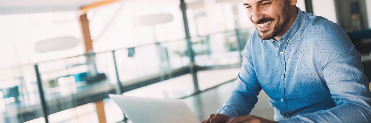 A man smiling while using his laptop.