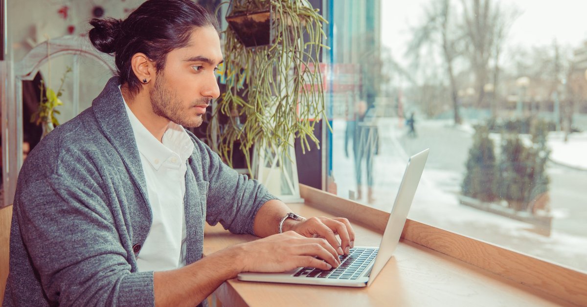 A man working on his laptop sitting in a cafe.