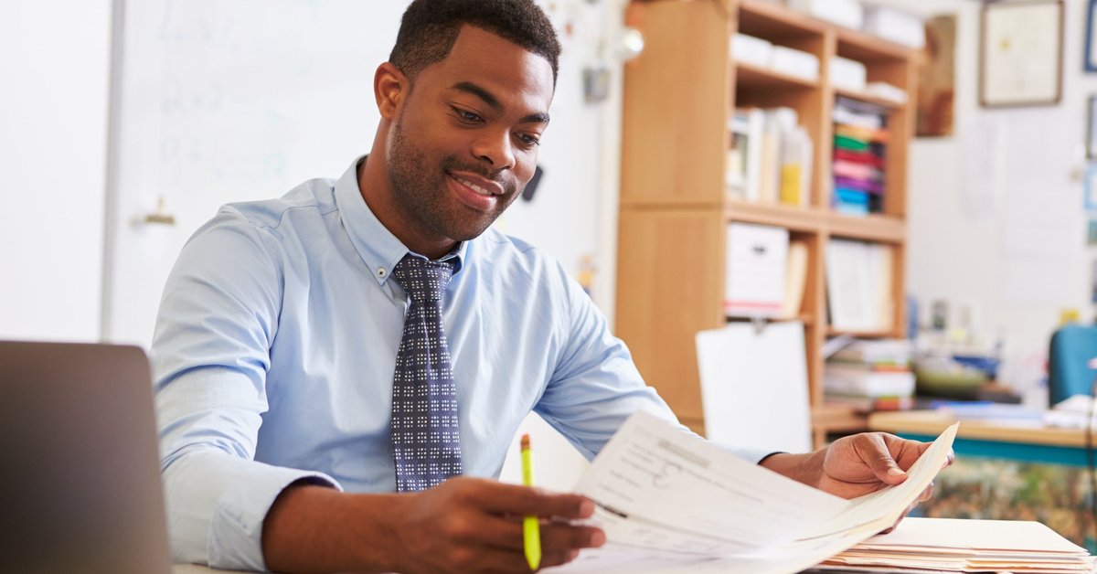 A man reading paperwork at his desk.